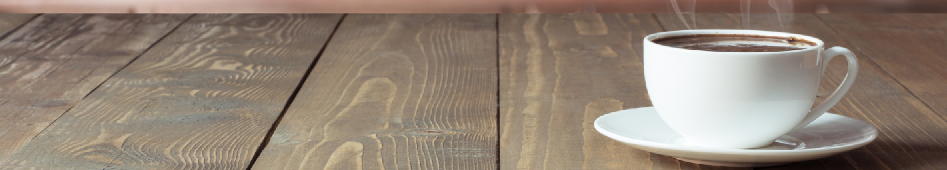 Cup of black coffee on wooden tabletop in blurred modern kitchen. Close up. Indoors.